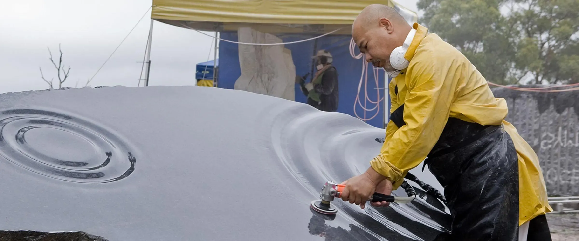 Man sculpting a stone to look like ripples on a lake